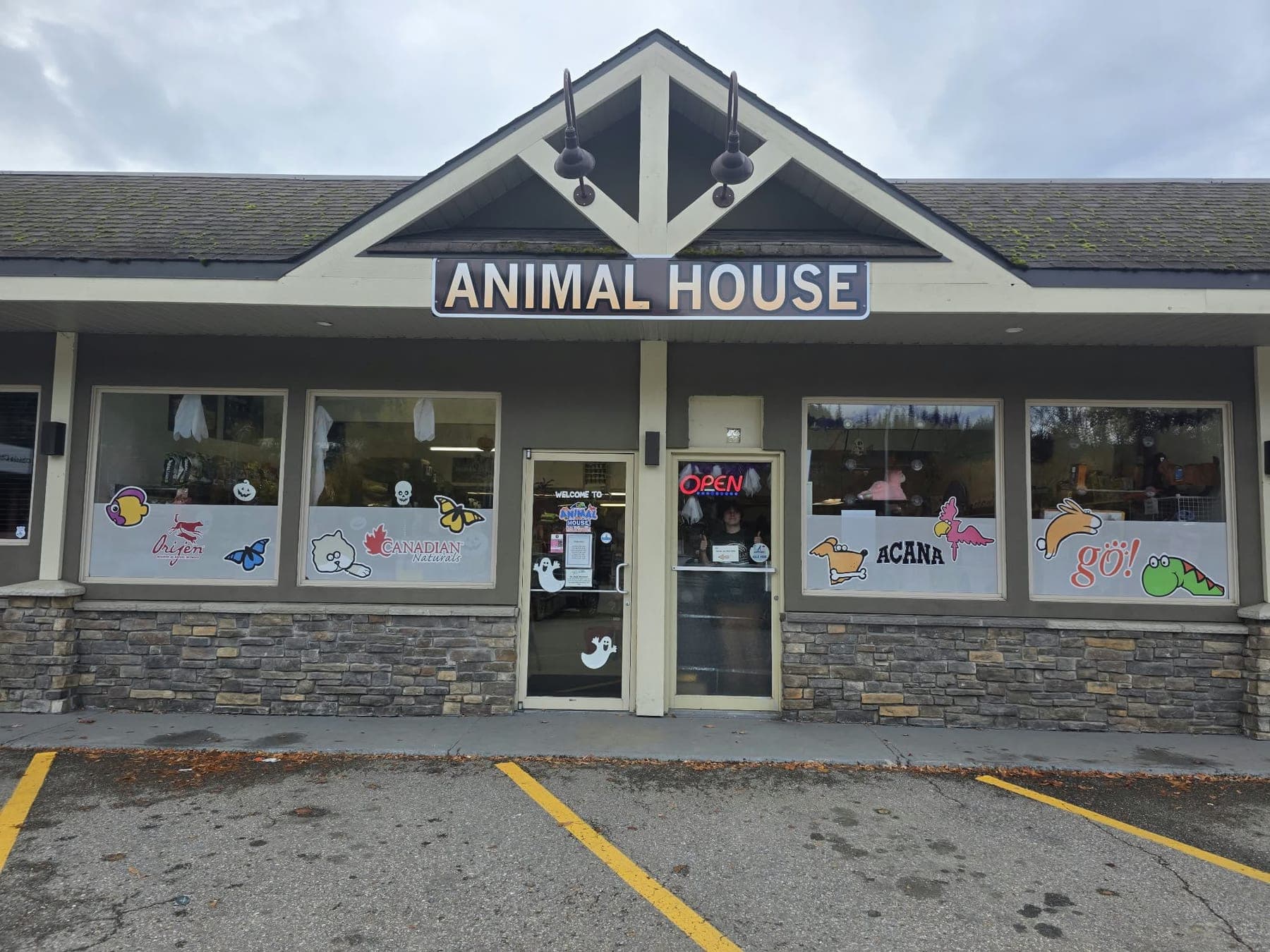 The Animal House storefront in Revelstoke: the Animal House sign on a peaked roof above windows decorated with pets and brand logos