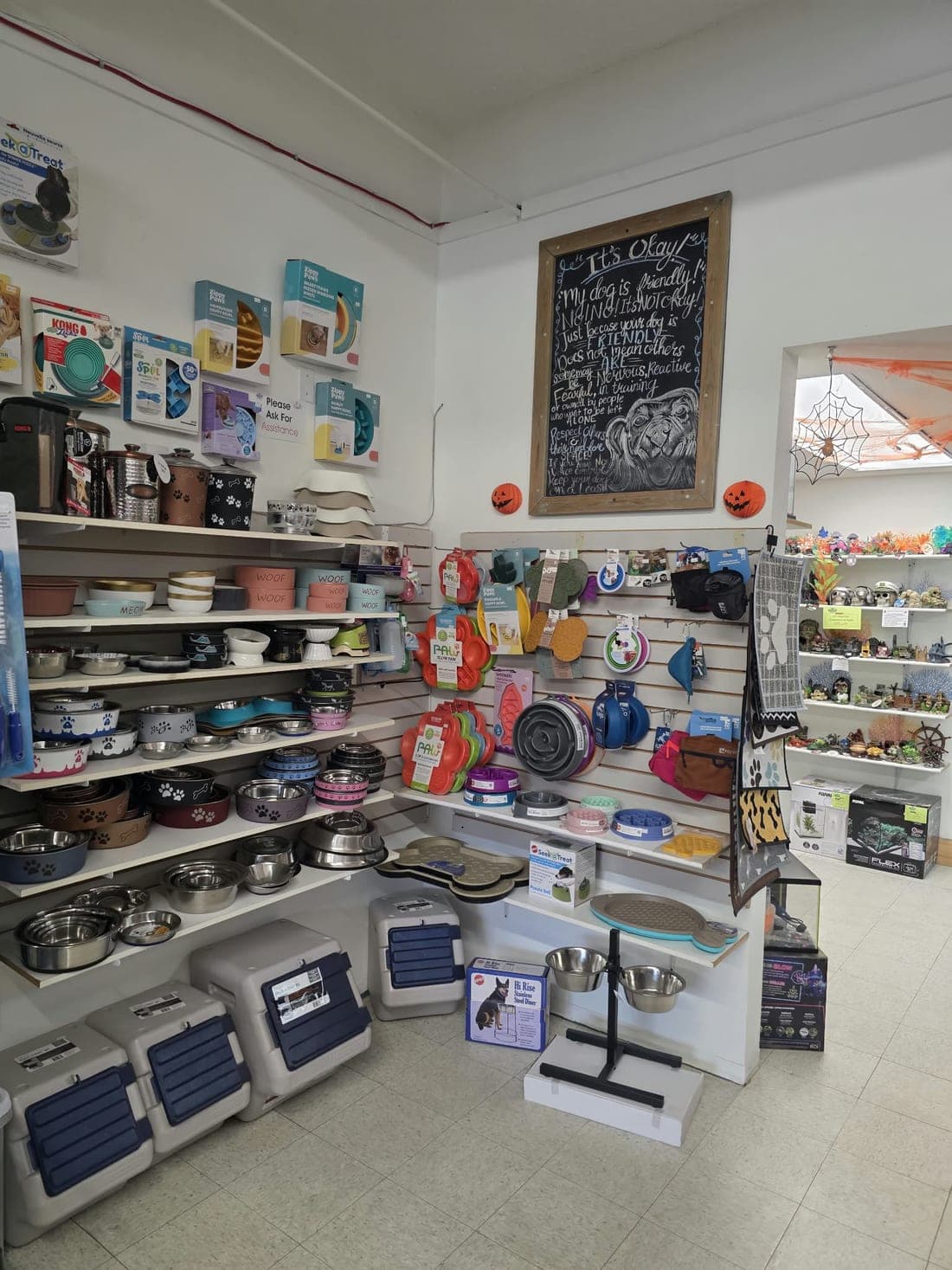 A corner of pet bowls, feeders and crates under a hand-written chalkboard at the Revelstoke store
