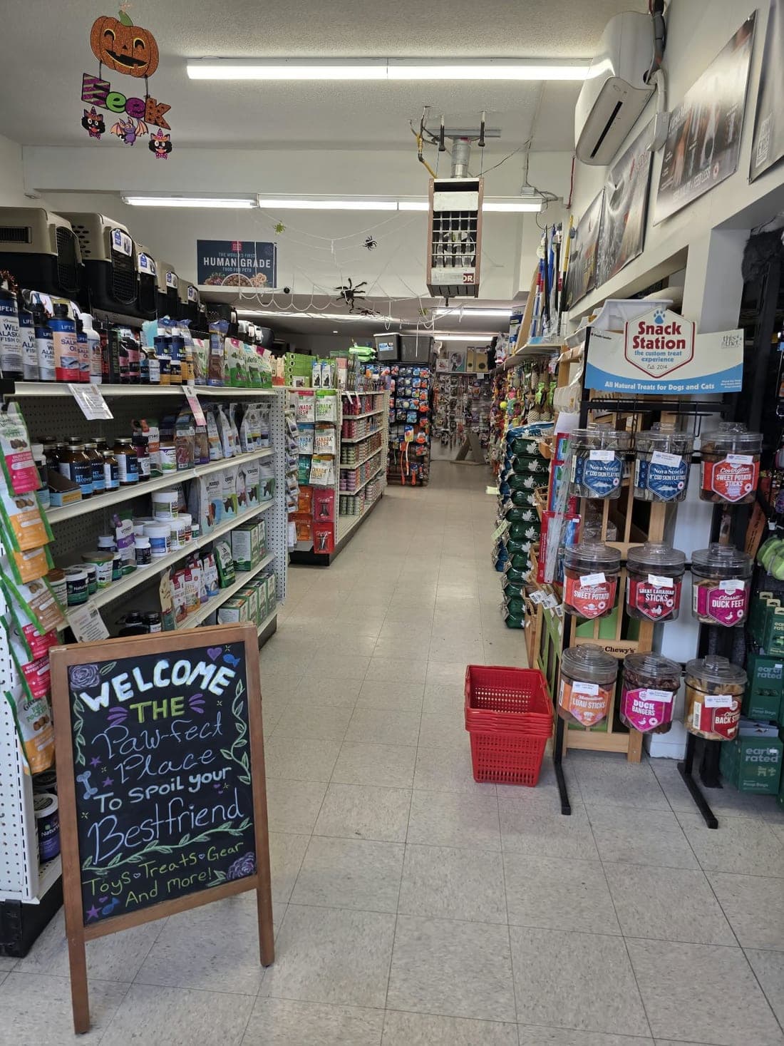 A Welcome chalkboard at the end of a long aisle of pet supplies in the Revelstoke store