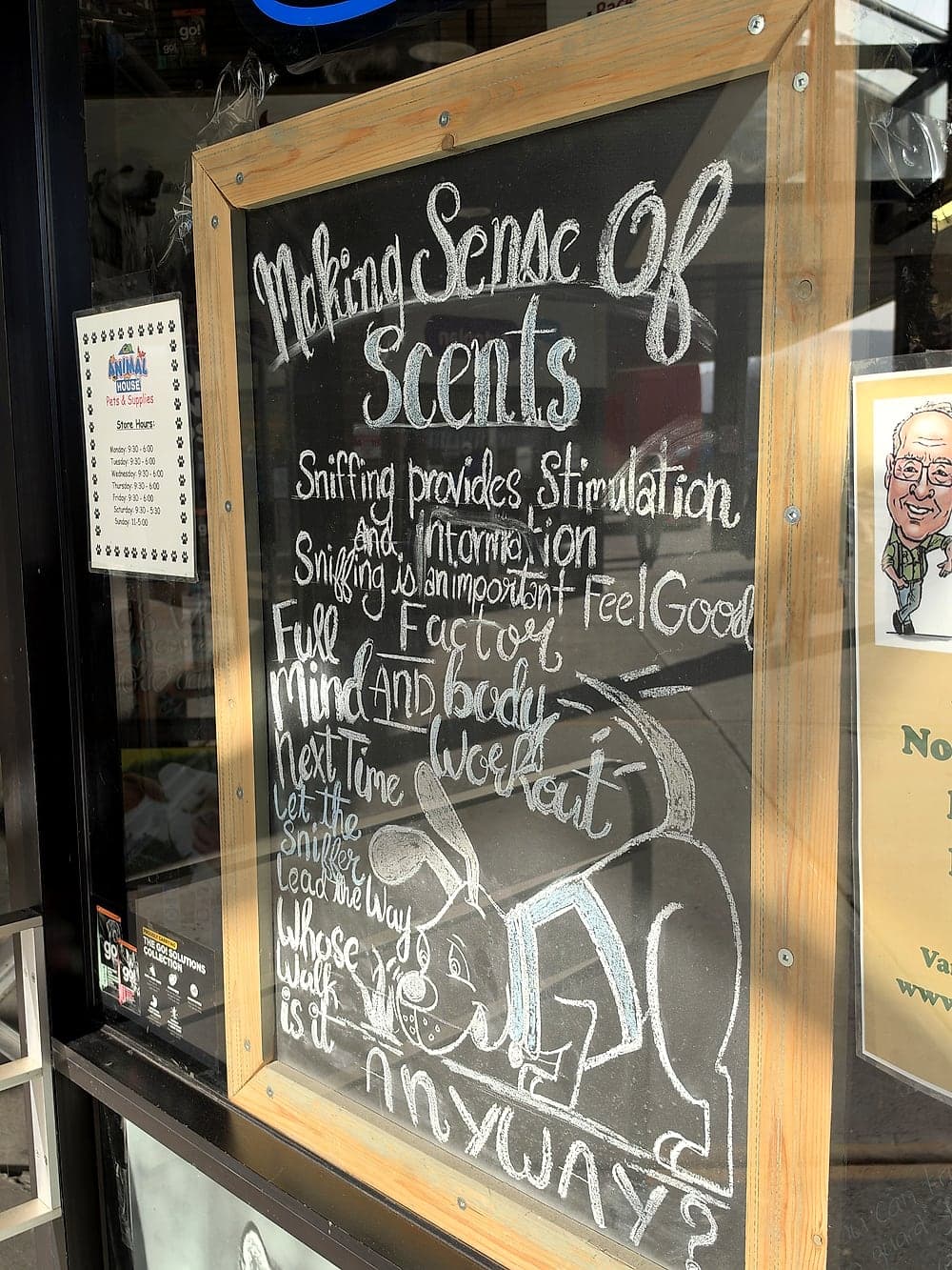 A hand-written chalkboard sign in the window about the benefits of sniffing for dogs
