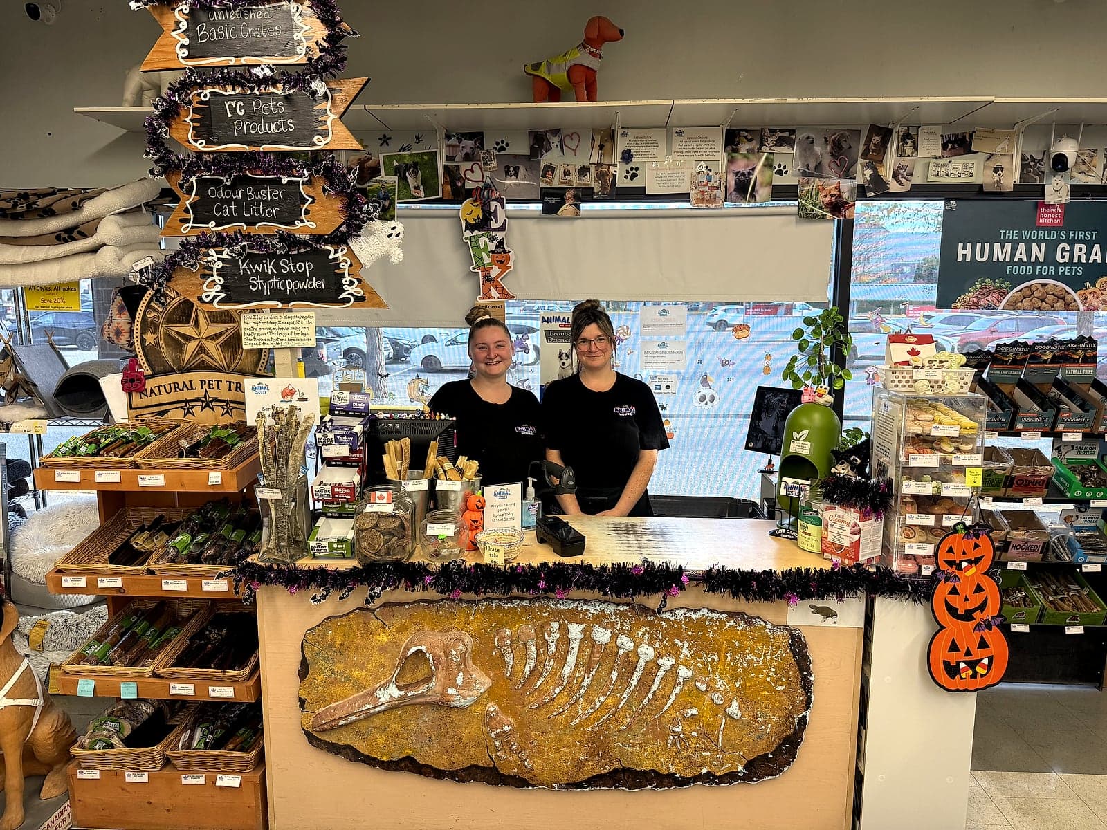 Two smiling Animal House staff behind the front counter with its fossil-carved front