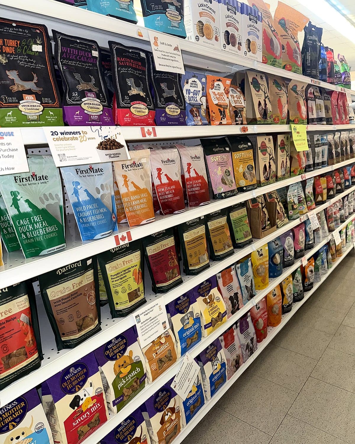 A long aisle of shelves stocked with bags of pet treats and food